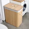 A bamboo laundry basket with a lid and rope handles is placed next to a washing machine. Náhled obrázku produktu