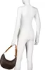A mannequin wearing a white long-sleeved shirt and white pants, holding a brown handbag. Produktbild-Vorschau
