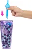 A hand is holding a blue straw over a purple cup filled with surprise items. Voir les images du produit