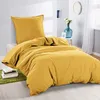 A yellow duvet cover and pillow are neatly arranged on a bed, with a small stack of books on a green rug in the foreground. Produktbild-Vorschau