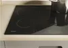 A close-up shot of a black induction cooktop on a light-colored countertop. Produktbild-Vorschau