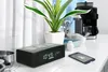A Lenco CR-580BK stereo FM-radiowecker is shown on a kitchen counter, charging a smartphone wirelessly. Other kitchen appliances and a plant are visible in the background. Produktbild-Vorschau