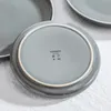 The underside of a gray ceramic plate with brand markings. Náhled obrázku produktu