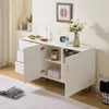 A white sideboard with gold accents in a well-lit room, with a book on the floor in front of it. Produktbild-Vorschau