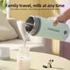 A hand is pouring water from a portable kettle into a baby bottle. Produktbild-Vorschau
