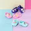 A collection of colorful children's shoes with decorative pins, arranged on a pastel-colored background. Podgląd zdjęcia produktu