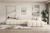 A modern living room with a large beige sectional sofa, abstract art on the wall, and a large potted plant. Produktbild-Vorschau