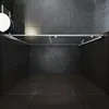 A modern, minimalist shower enclosure with a glass door and silver frame, set against dark tiled walls and floor. Anteprima dell’immagine prodotto