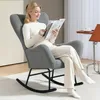A woman is sitting in a rocking chair reading a magazine. Anteprima dell’immagine prodotto
