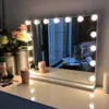 A vanity mirror with lights on a dresser, with some makeup and flowers. Produktbild-Vorschau