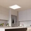 A modern kitchen with white cabinets, a stainless steel refrigerator, and a large LED panel light hanging from the ceiling. Produktbild-Vorschau