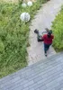 A person is pushing a Kärcher KM 70/20 C 2SB sweeper down a paved path next to a garden. Anteprima dell’immagine prodotto