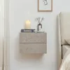 A wall-mounted nightstand with two drawers, decorated with a candle and a small vase with flowers. Anteprima dell’immagine prodotto