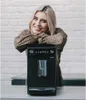 A woman is leaning on a coffee machine. Produktbild-Vorschau