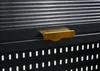 A close-up view of a black cabinet with a gold handle and a ribbed surface above it. The lower part of the cabinet has a perforated pattern. Anteprima dell’immagine prodotto