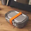 A stainless steel lunch box with an orange strap sits on a wooden surface. Podgląd zdjęcia produktu