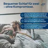 A couple is lying in bed, embracing under the covers. Produktbild-Vorschau
