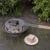 A sandwich maker is being used on a grill over coals, with a sandwich on a plate nearby. Anteprima dell’immagine prodotto