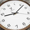 A close-up view of a wooden wall clock with a white face and black hands. Voir les images du produit