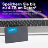 A Crucial SSD is placed in front of a laptop, with marketing text overlayed on the laptop screen. Produktbild-Vorschau
