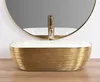 A gold and white basin with a gold faucet in front of a round mirror. Náhľad obrázku produktu