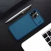 A blue phone case with a camera cover is placed on a dark surface next to a pen and a laptop. Náhľad obrázku produktu