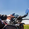 A person's hand is shown adjusting a smartphone mounted on a motorcycle handlebar. Produktbild-Vorschau