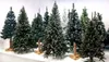 A collection of artificial Christmas trees of various sizes and styles are displayed on a white surface against a light gray background. Voir les images du produit