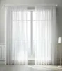 A pair of white sheer curtains hanging in front of a large window. Produktbild-Vorschau