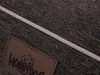 A close-up view of a dog bed's textured fabric and a leather label. Náhľad obrázku produktu