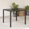A square patio table with a glass top and rattan-like base is shown on a tiled patio. There are potted plants in the background. Náhled obrázku produktu