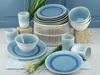 A collection of blue and white ceramic tableware, including plates, bowls, and cups, arranged on a light blue cloth and stone props. Náhľad obrázku produktu