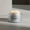 A jar of Babor The Cure Cream is placed on a light gray surface with a white background element behind it. Podgląd zdjęcia produktu