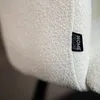 A close-up of a textured white fabric with a black label attached. Produktbild-Vorschau