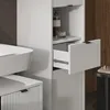 A close-up of a modern white bathroom cabinet with a drawer partially open, next to a white sink. Náhled obrázku produktu
