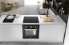 A modern kitchen counter with a built-in oven and induction hob, featuring food preparation. Produktbild-Vorschau