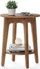 A round wooden side table with a plant, books, and a lamp on it, set against a white background. Produktbild-Vorschau