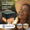 A woman wearing a straw hat is laughing outdoors, with a rattan garden table in the foreground and smaller images of similar tables in different colors at the bottom. Produktbild-Vorschau