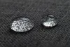 Close-up of two water droplets on a dark gray textured surface. Produktbild-Vorschau