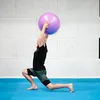 A man is performing a lunge exercise with a large purple exercise ball overhead. Voir les images du produit