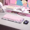 A pink mechanical keyboard and mouse are set up on a desk with a monitor in the background. Produktbild-Vorschau