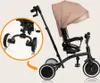 A three-wheeled stroller/tricycle with a canopy and a parent handle, shown against a light gray background. An inset circle highlights the front wheel assembly. Anteprima dell’immagine prodotto