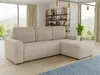 A beige corduroy sectional sofa is shown in a well-lit living room with a large window overlooking a natural landscape.