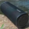 A black portable speaker is placed on rocks near water. Náhled obrázku produktu