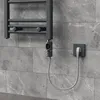 A close-up view of a grey electric towel rail mounted on a grey tiled wall, plugged into a wall socket. Náhled obrázku produktu
