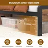Under-bed storage space with various storage containers, including a clear plastic box and a woven basket, with a height measurement of 23cm indicated. Icons at the bottom suggest storage box, shoe box, robot vacuum, and suitcase. Produktbild-Vorschau