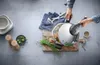 A person is using a pressure cooker on a wooden board with ingredients around it. Náhled obrázku produktu