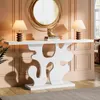 A white console table with a decorative base is set against a pink paneled wall, adorned with two lamps, books, and an owl figurine. A large, circular gold mirror hangs above the table. Anteprima dell’immagine prodotto