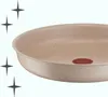 A close-up view of a speckled beige frying pan with a red Tefal logo visible. Podgląd zdjęcia produktu