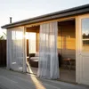 A covered outdoor seating area with sheer curtains, furniture, and a small table. Voir les images du produit